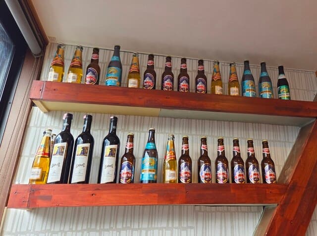Wooden shelves lined with Himalayan and Indian beer bottles at the bar